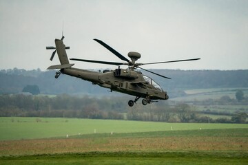 Military helicopter landing in a field