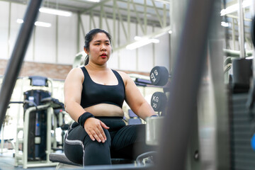 Fototapeta na wymiar chubby motivated woman pulling workout machine. female gym member holding in heavy weight fighting to build strong muscle. determined person aim for changing life practice pulling up workout station