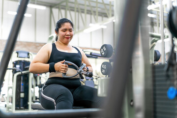 chubby motivated woman pulling workout machine. female gym member holding in heavy weight fighting to build strong muscle. determined person aim for changing life practice pulling up workout station