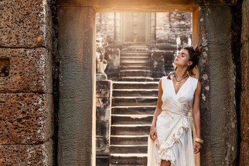 Young woman wearing white robe dress in ancient Khmer ruins, Angkor Wat