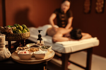 Healthy spa set on a table with customer relaxation massage on background. - obrazy, fototapety, plakaty