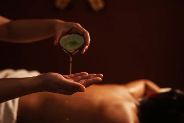 Stickers pour porte Salon de massage Masseur pouring aroma oil on hand, for massage on back of customer. Relaxation young male customer get service aromatherapy massage with masseuse in spa salon.
