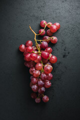 Branch of red grapes on a dark background.