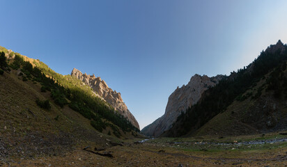 A massive rock pass, illuminated by morning light, in the Turkestan Mountains of Kyrgyzstan.