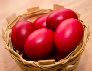 Closeup of red Easter eggs in a basket on a wooden table