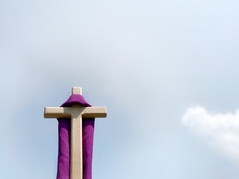 Lent Season,Holy Week and Good Friday concepts - image of wooden cross with purple shawl with sky background. Symbolism of Jesus Christ has risen.
