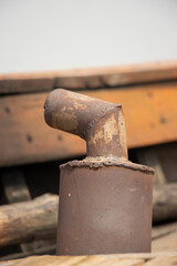 Ship exhaust pipe close-up shot on a blurry background. A Rusty exhaust pipe on a ship. Dirty smoke funnel on a wooden boat. Smoke chimney and exhaust pipe. Old and rusty smoke funnel on a ship.