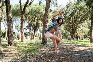 Happy man slacklining in the city park during summer day