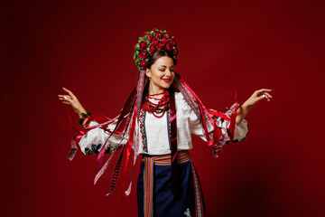 Portrait of ukrainian woman in traditional ethnic clothing and floral red wreath on viva magenta studio background. Ukrainian national embroidered dress call vyshyvanka. Pray for Ukraine - 590780906