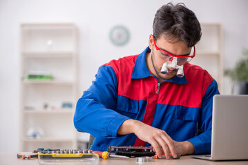 Young male repairman repairing computer