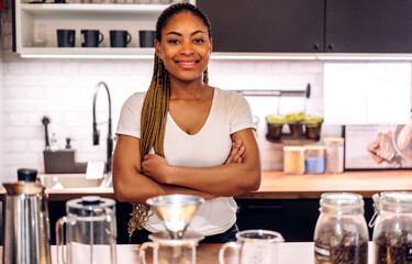 Portrait of african american barista woman small business owner working behind the counter bar and receive order from customer on coffee packaging and cup of coffee background in cafe or coffee shop