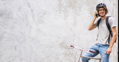 Obraz premium Portrait of casual hipster handsome businessman with backpack looking forward while commuting riding bicycle on the street city way go to work.business travel transport bike concept