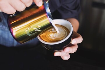 Close up Barista hands making latte in coffee bar.
