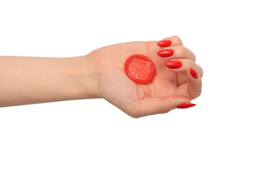 A red condom in a woman hand with red nails isolated on white background.