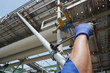 Worker's hand holding a wrench to installation scaffolding work for support building construction...