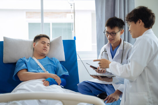 Physical injury treatment: Serious doctors are analyzing fracture patients. Young man with broken arm talking to trauma doctor or orthopedic surgeon during physical examination in hospital or clinic