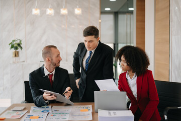 Happy businesspeople while collaborating on a new project in an office. Group of diverse businesspeople using a laptop and tablet in office..