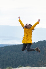 Portrait of girl jumping on top of mountain. Happy tourist woman conquered the top. Concept of freedom.