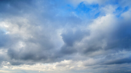 Naklejka na ściany i meble Dramatic sky with dark cumulus clouds. Menacing heavy clouds in the blue sky