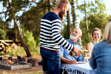 Man pouring friends wine outdoors