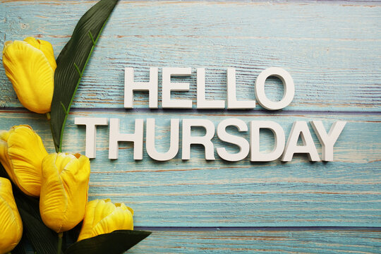 Hello Thursday alphabet with yellow tulip flower on wooden background