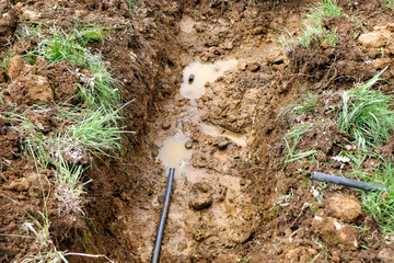 Broken water pipe with water leaking out into the soil
