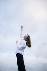 Fototapeta na wymiar Brunette girl with raised arms against the sky