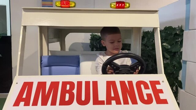 Preschool kid playing in wooden ambulance truck. High quality FullHD footage