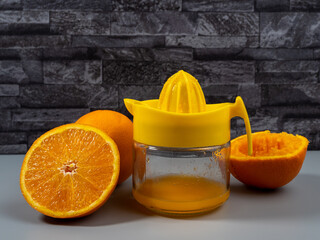 Orange juicer with ripe oranges. Fresh juice. Gray background.