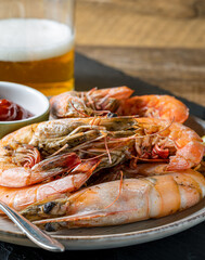 Sauteed shrimp on a plate, glass of beer in the background.