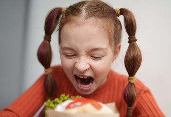 Funny white girl biting a sandwich. Portrait of cute 9 year old kid eating a pita souvlaki snack in a Greek fast food restaurant