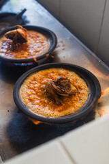Sambal iga or ribs with sambal cooked in earthenware plate against wooden background. Served on wooden table