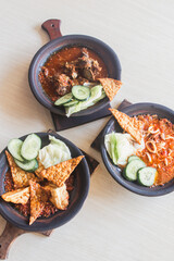 Sambal gami cumi or squid with sambal cooked in earthenware plate against wooden background. Served on wooden table