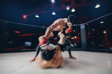 MMA sport, Boxers fighter finishes off enemy in ring octagon, dark background spot light