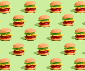 Creative pattern made with jelly gummy hamburgers on a green background.