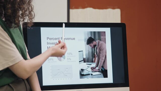 Medium close-up shot of hands and body of anonymous female company worker displaying presentation slide on screen, pointing and explaining details