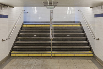 Subway stairs with hand rails, low ceilings and tiled walls