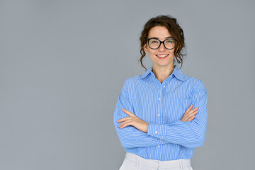 Happy young smiling confident professional business woman wearing blue shirt and glasses, happy pretty female executive looking at camera, standing arms crossed isolated at gray background, portrait.