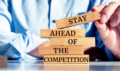 Close up on businessman holding a wooden block with "Stay ahead of the competition" message