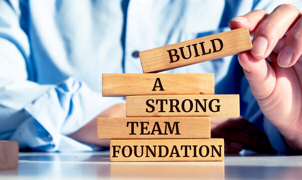 Close up on businessman holding a wooden block with "Build a strong team foundation" message