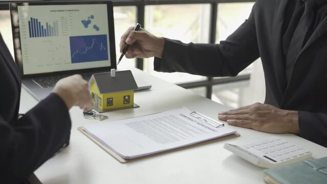 Real estate brokers present and advise clients on the decision to sign insurance contracts. Buy and sell a house Loan offer with office handshake
