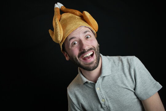 Man on black background is wearing turkey hat. 
