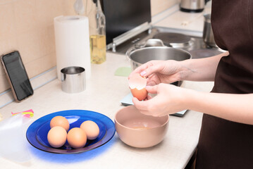 Woman adding egg whites in bowl making homemade meringue cake Pavlova by online recipe from her phone. Selective focus. Process of cooking at home concept