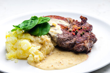 beef steak with sauce, mashed potatoes and spinach leaves