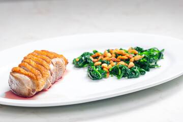 roasted duck breast served with salad of spinach leaves and pine nuts