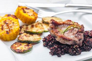 grilled pork steak with zucchini and corn served with black quinoa