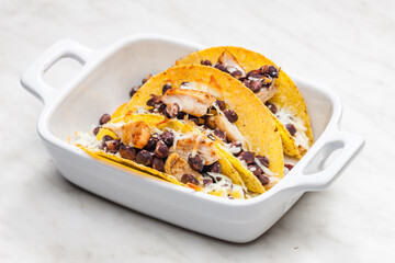 tacos filled with grilled chicken meat, red beans and grated cheese