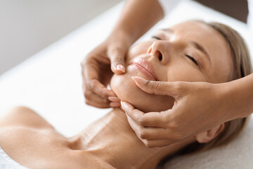 Beautiful Middle Aged Woman Getting Face Lifting Massage In Luxury Spa Salon