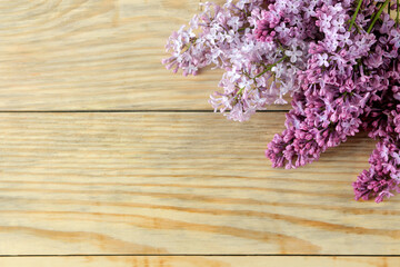 Frame of spring lilac twigs on a natural wooden table. top view. place for an inscription.