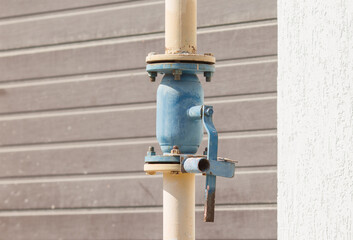 yellow old gas pipe with a valve on the wall of the house
